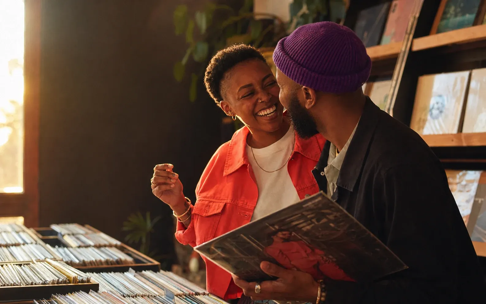 Two adults laughing together while browsing records in a warm, sunlit shop